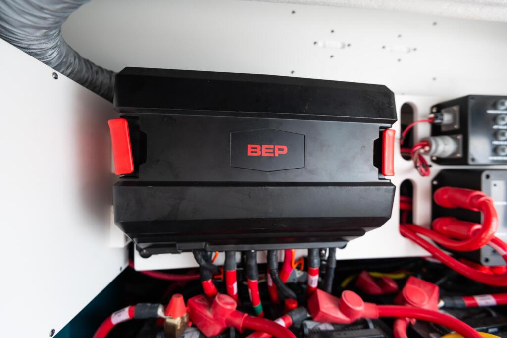 Close-up of a BEP 100-amp battery charger mounted under a boat hardtop with red electrical connections