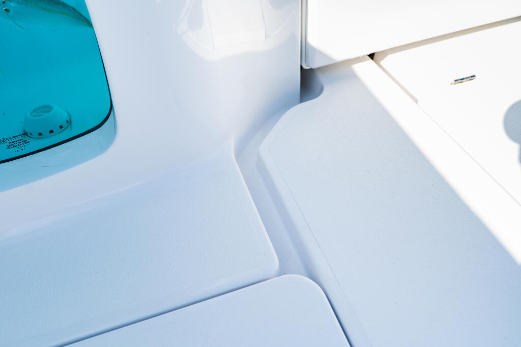 Close-up of white boat seating and gutter system with blue windshield in bright sunlight