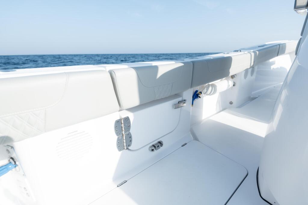 Spacious boat deck with white upholstered seating, open side-entry door, and calm blue ocean horizon