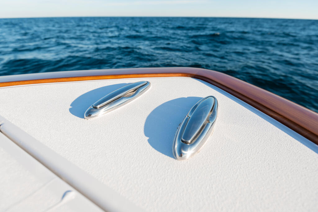 Chrome cleats on white fiberglass deck with ocean water in background