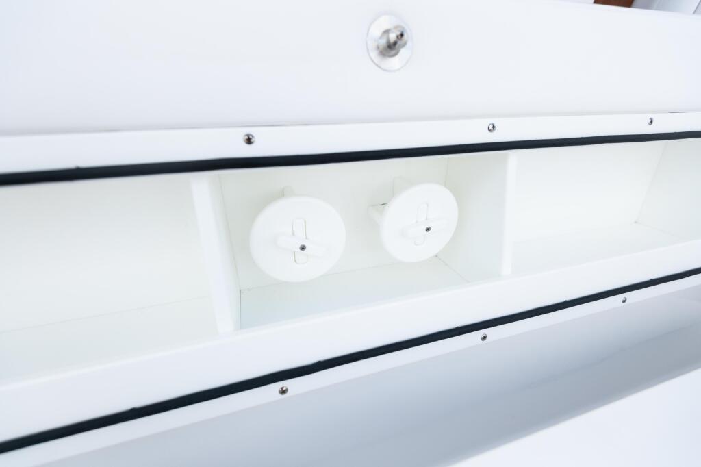 Overhead view of white livewell with two circular flush-mount hatches and black trim rails on boat gunwale