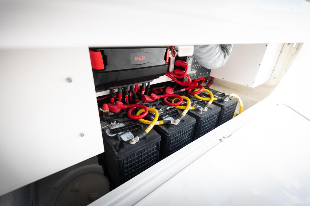 Multiple black battery boxes with red cable connectors and yellow terminals installed in boat storage compartment
