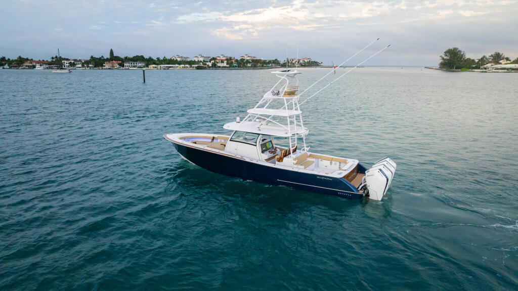 Sport fishing boat anchored in calm turquoise water with residential shoreline in the background
