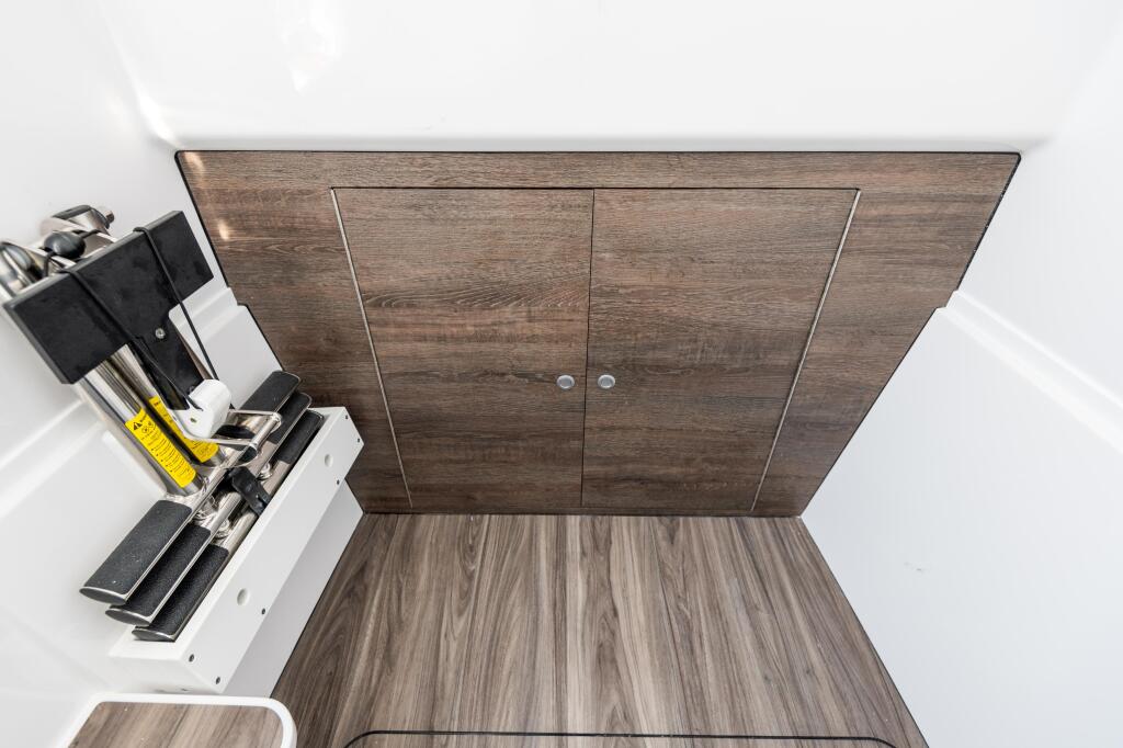 Overhead view of boat cabin storage with dark wood doors and tackle box storage along the side