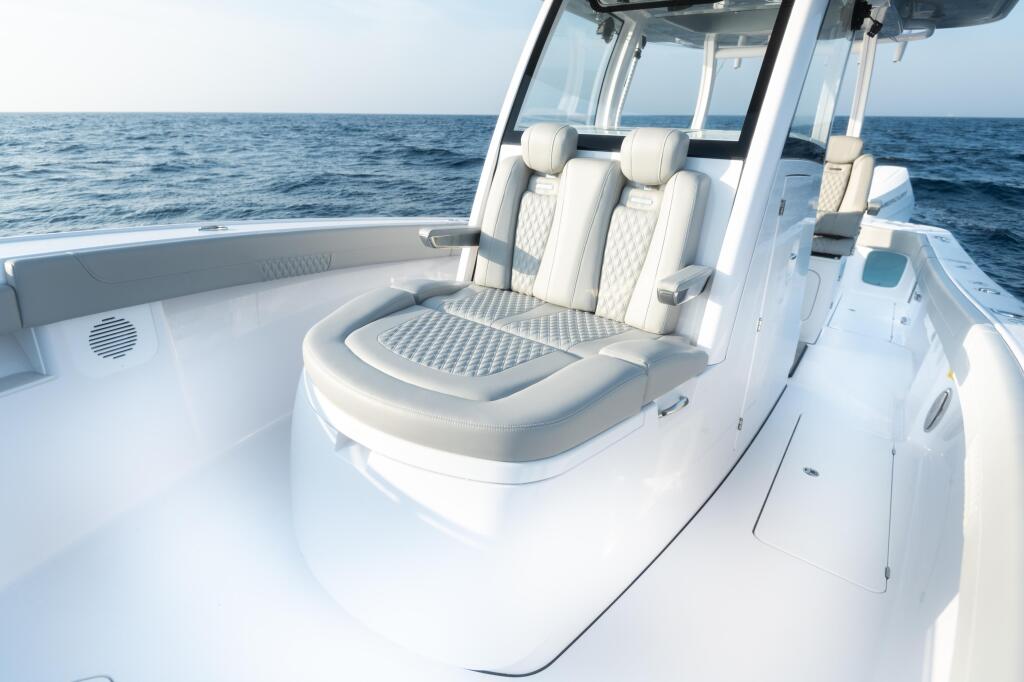 Cream-upholstered seating with armrests and windshield aboard a white center console boat on open ocean