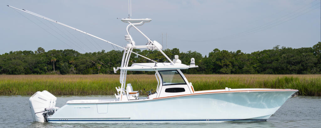 White center console boat with tall T-top and electronics mounted in shallow marsh waters