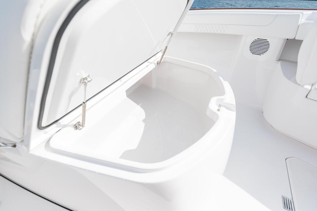 Open white insulated built-in cooler with curved seating integrated into boat interior