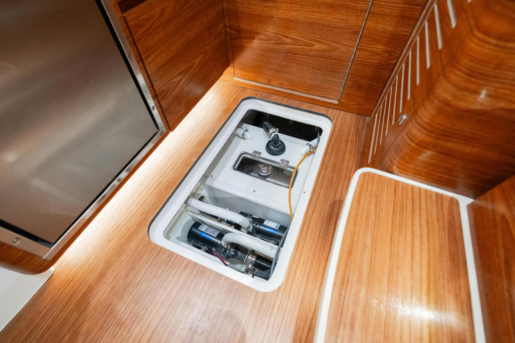 Open access hatch in teak cabin sole showing sump pump and electrical systems installation