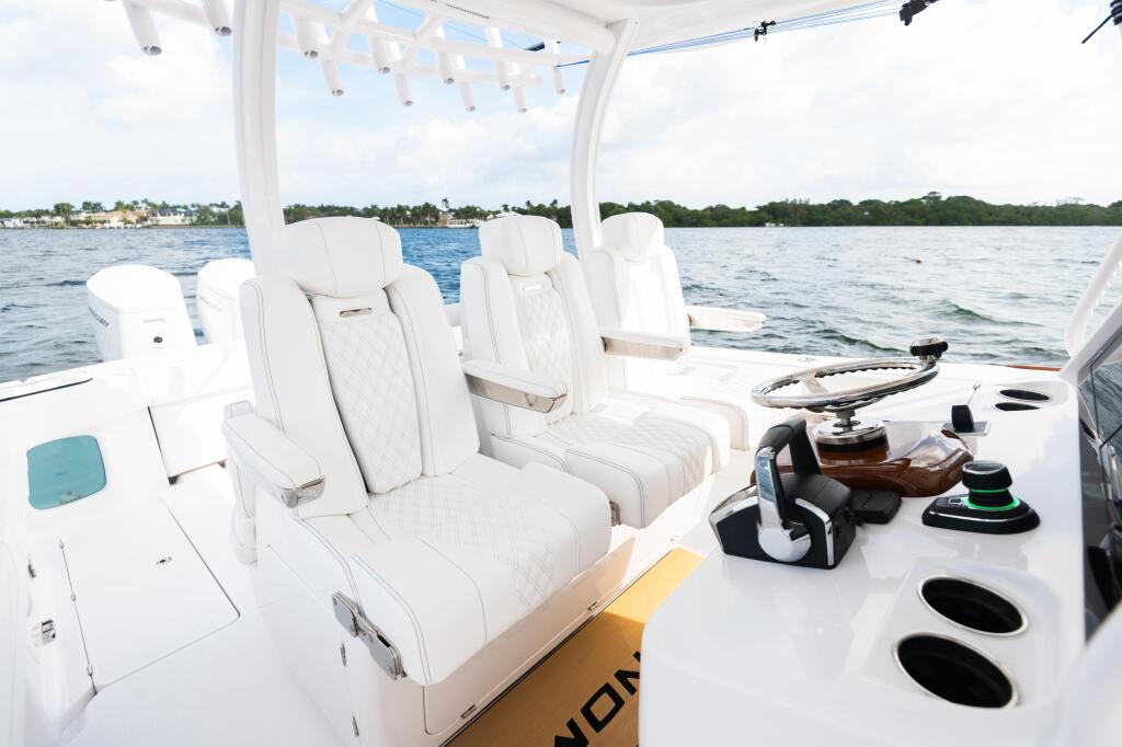 Spacious helm area with premium white leather seating, hardtop shade, and control console overlooking calm waters
