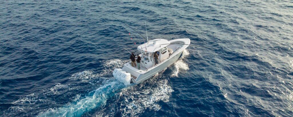 White fishing boat running offshore with wake trailing behind in deep blue water