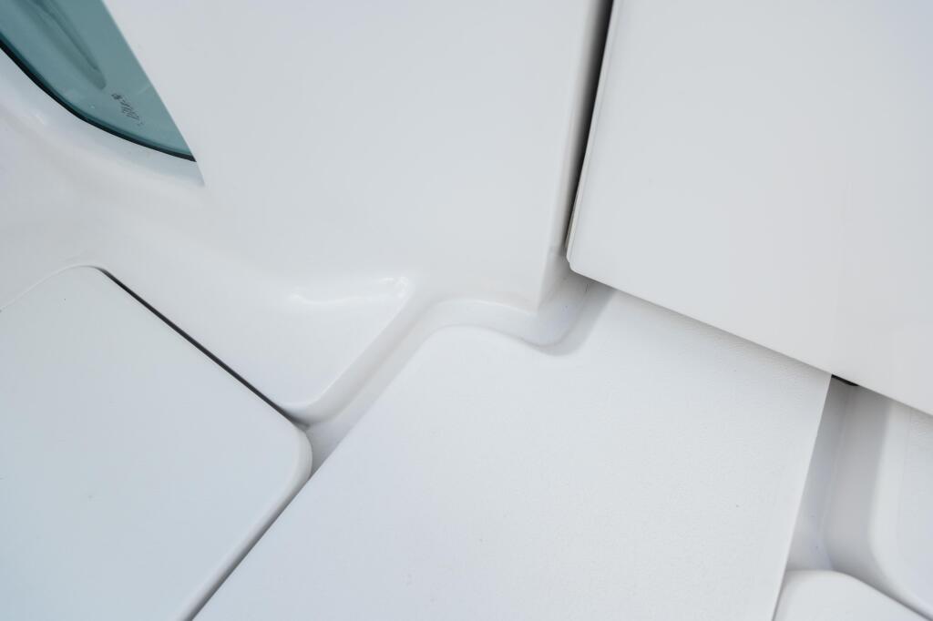 Close-up of white fiberglass boat seating with curved contours and self-bailing cockpit design
