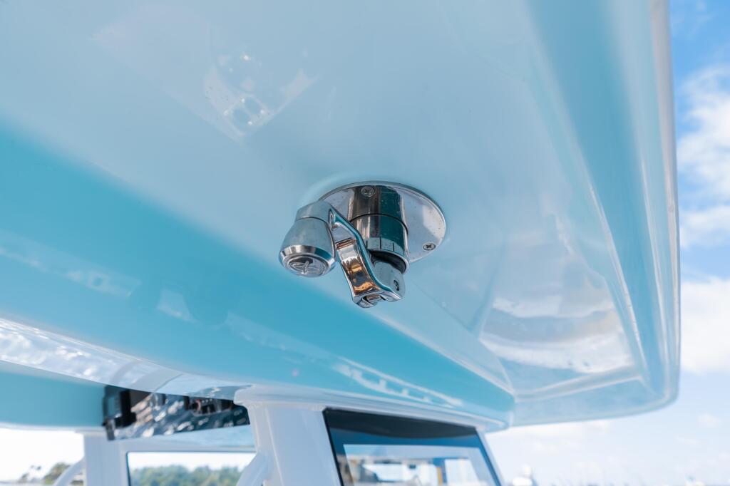 Chrome faucet and fixture mounted on light blue cabin ceiling with windshield visible below