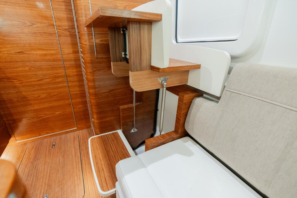 Boat cabin interior with wooden cabinetry, compact furniture, and storage compartments under steps