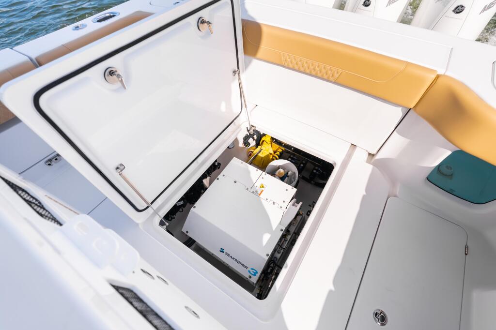 Open storage compartment revealing SeaKeeper gyroscopic stabilizer system with yellow housing and electronic components