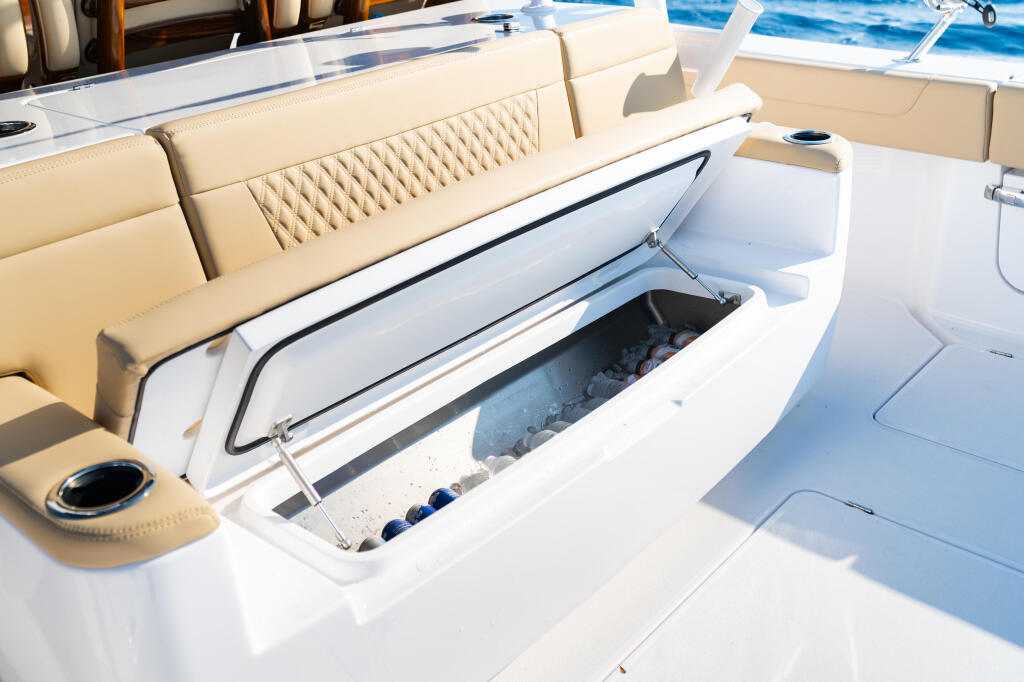 Open cooler with ice and beverages on boat deck with cream-colored seating in background