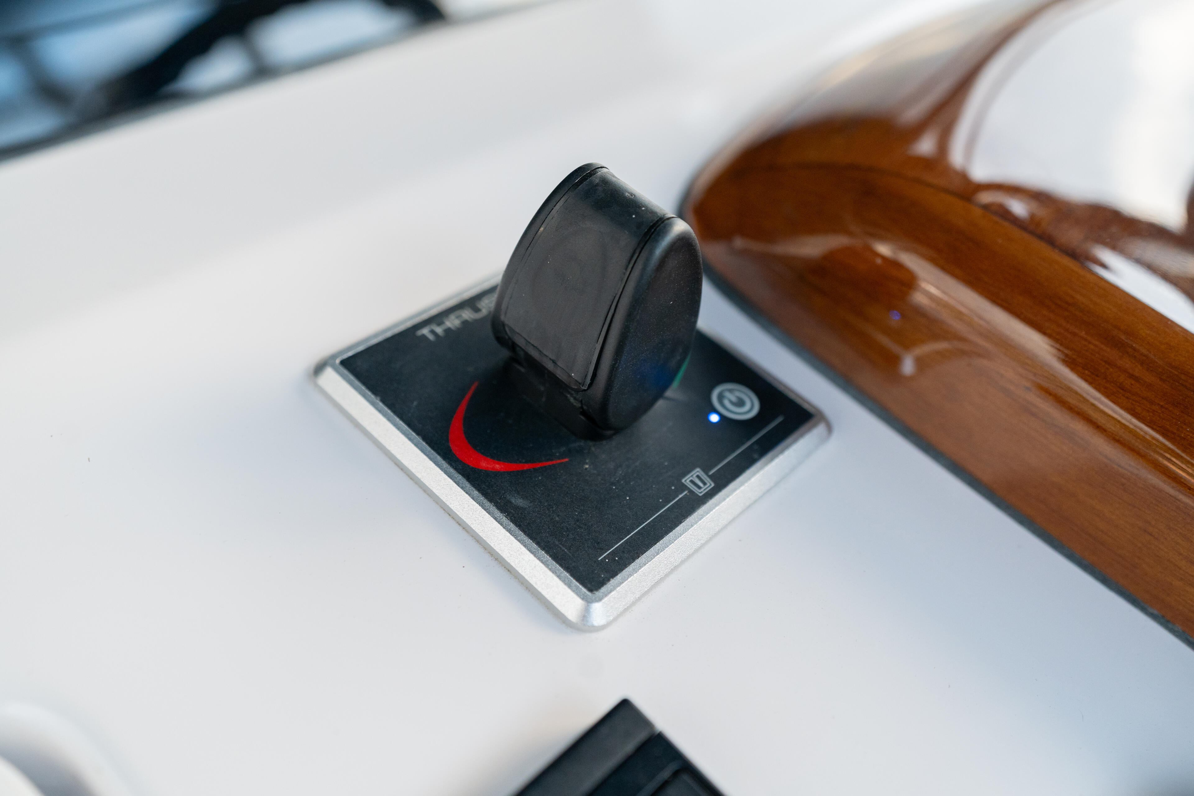 Boat helm control with thrust lever mounted on white fiberglass console with wooden trim
