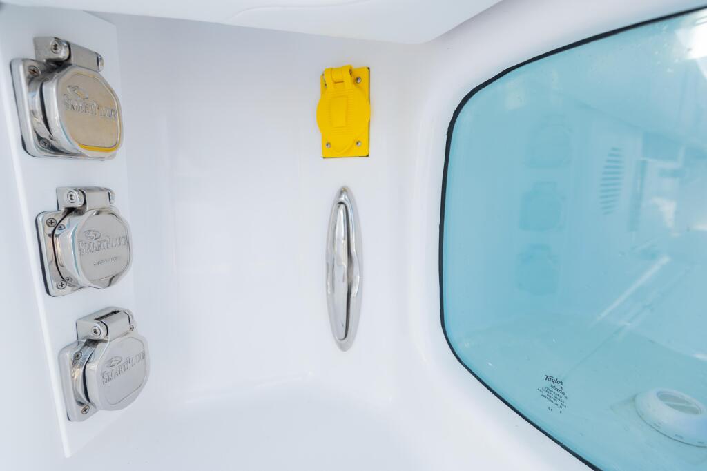 Cabin interior showing three stainless steel electrical outlets, yellow protective cover, chrome steering wheel, and tinted window