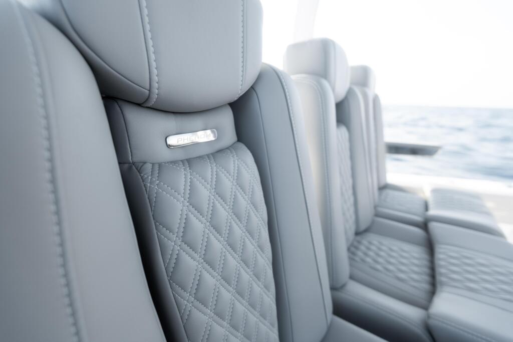 Close-up of gray quilted boat seating with chrome accents and water visible in background