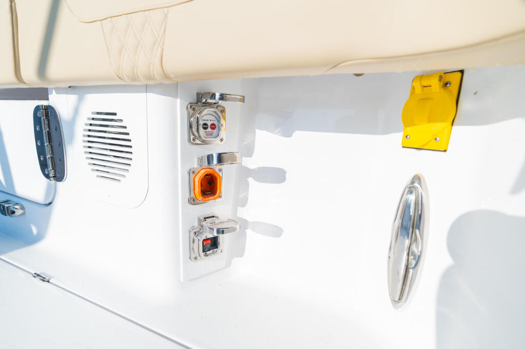 Boat control panel with electrical outlets, gauges, and switches mounted on white cabin wall
