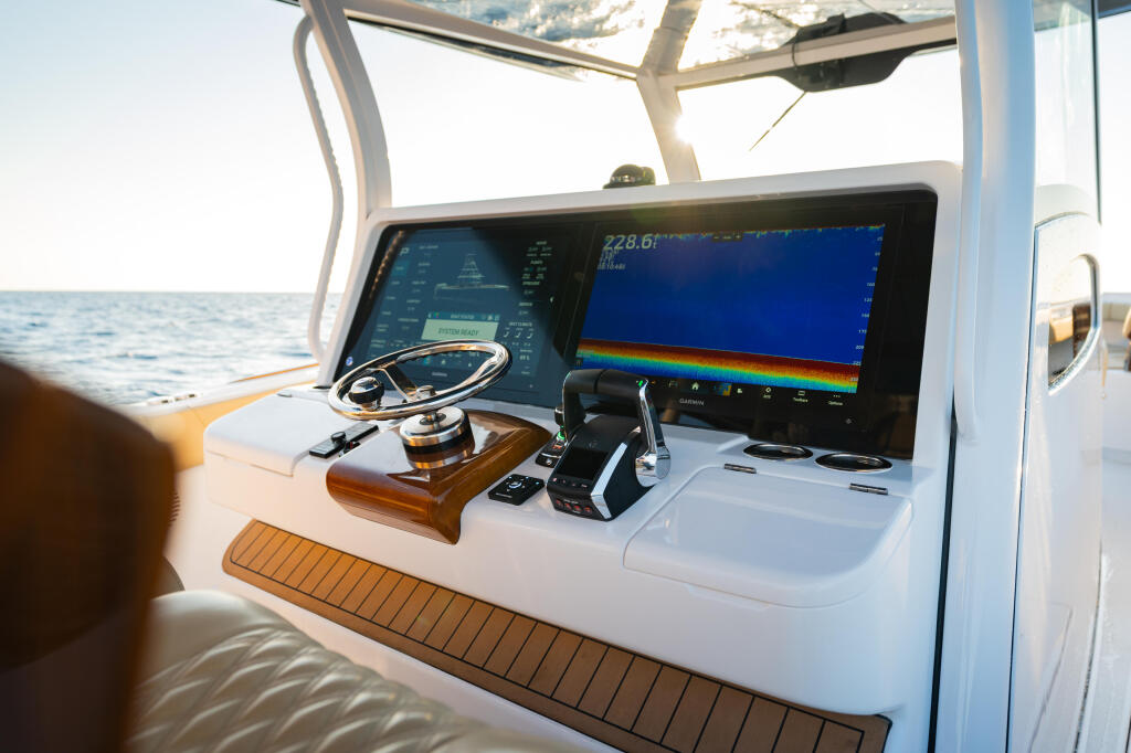 Modern boat helm station with dual electronic displays showing sonar readout and navigation instruments overlooking open ocean