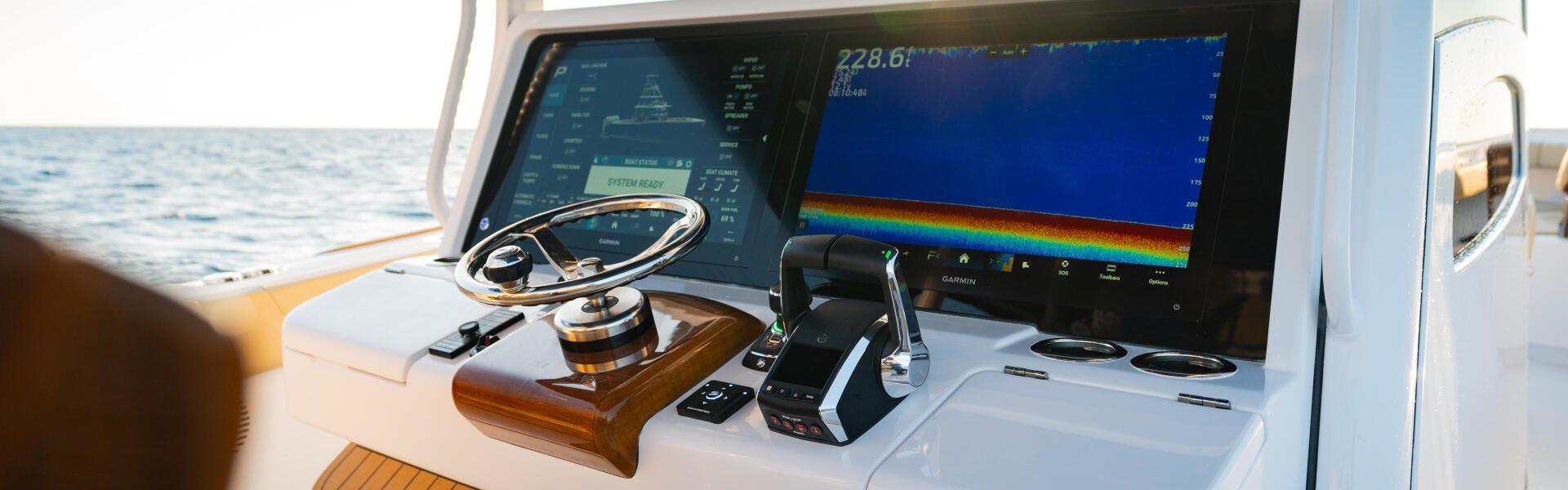 Modern boat helm station with dual electronic displays showing sonar readout and navigation instruments overlooking open ocean