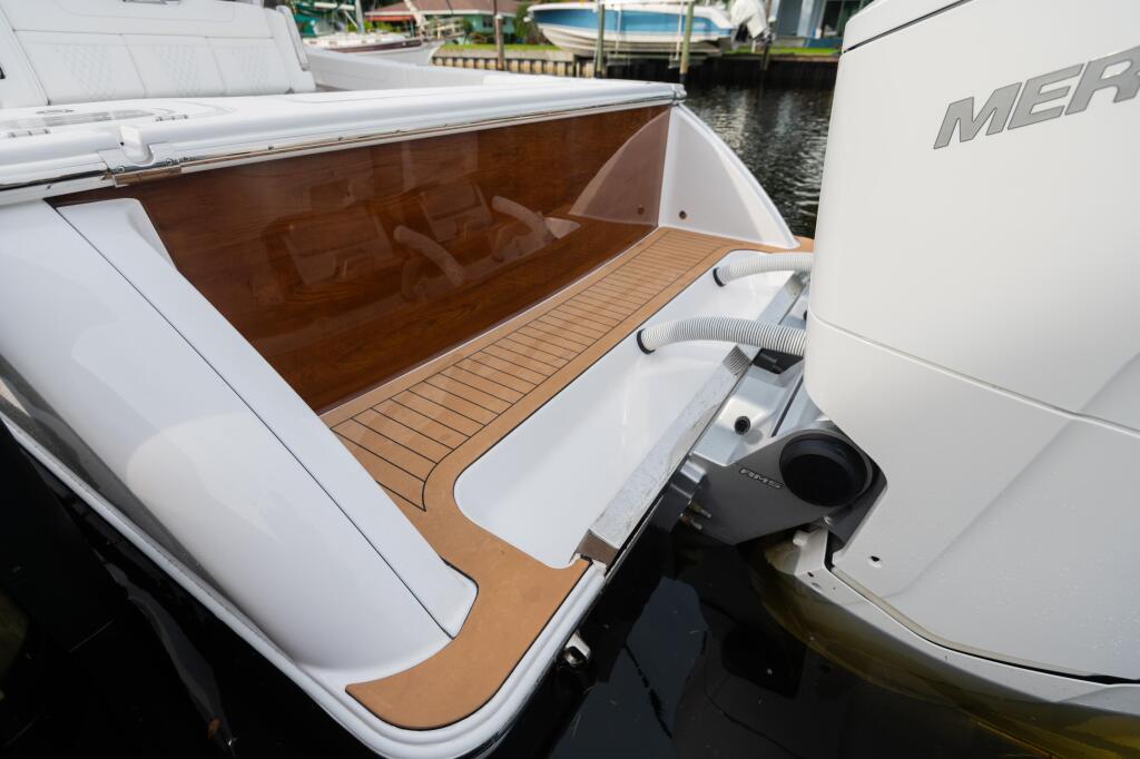 Open transom with faux teak decking and white fiberglass sides on a docked boat at a marina