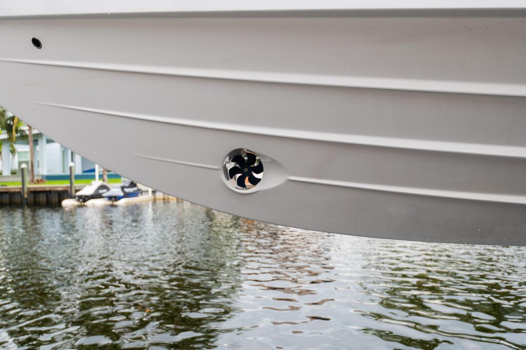 Ventilation fan on the side of a white boat hull docked in calm marina water