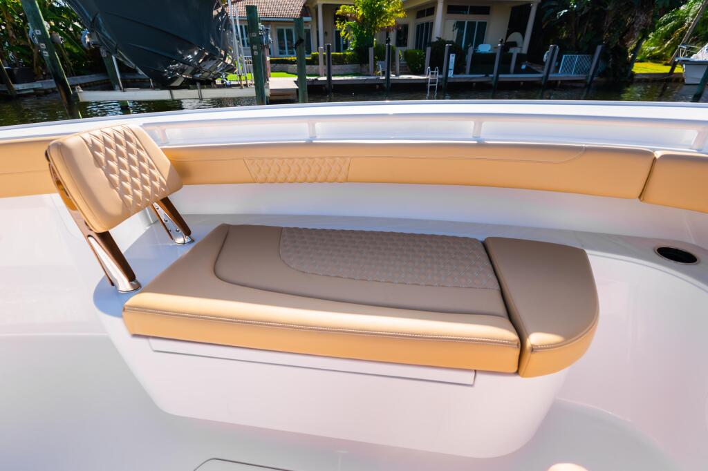Luxurious tan and gray cushioned seating in the bow of a sport boat docked at a waterfront home