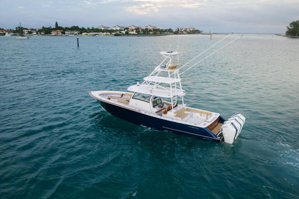 Sport fishing yacht anchored in calm coastal waters with residential shoreline visible in background