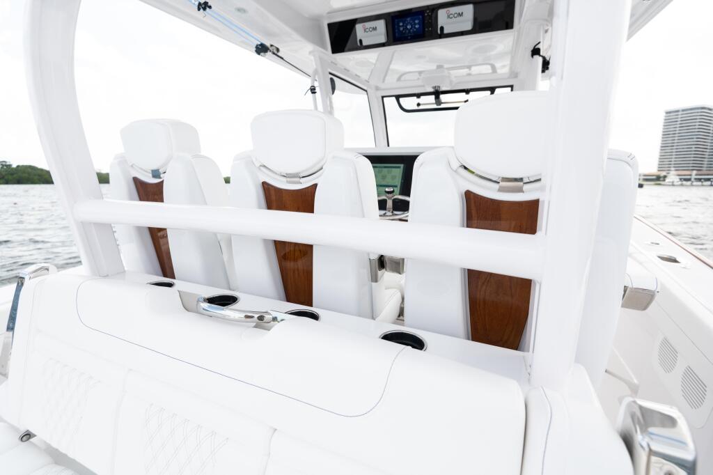 Helm console with white cushioned seats, wood accents, and electronics mounted overhead under hard-top canopy