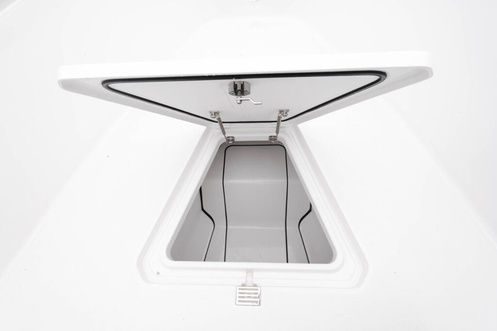 Overhead view of open white storage hatch with rubber gasket and chrome hardware on boat deck
