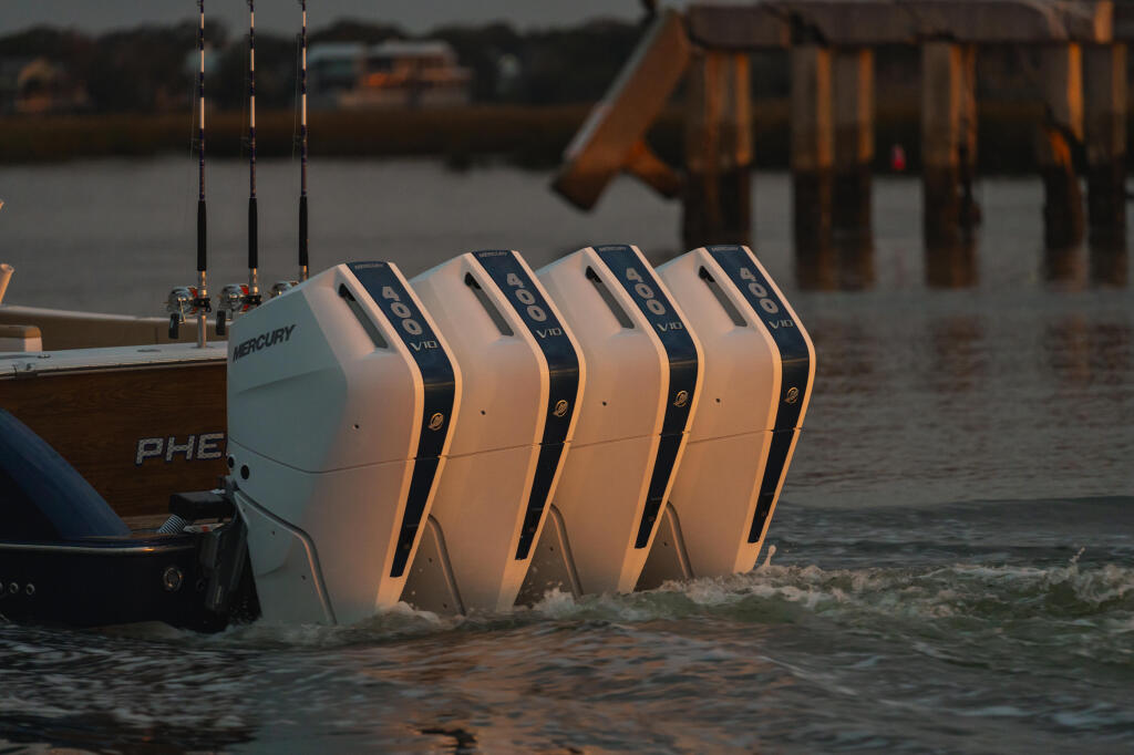Four Mercury Verado 400hp outboard engines mounted on a boat at a sandy beach with fishing rods visible