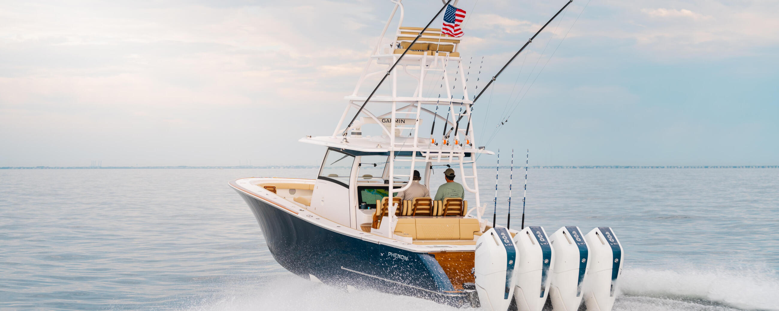 Sport fishing boat with quad engines running through shallow beach waves under clear sky