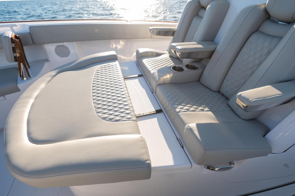 Spacious sun-lit cabin interior with gray upholstered seating, textured flooring, and water views