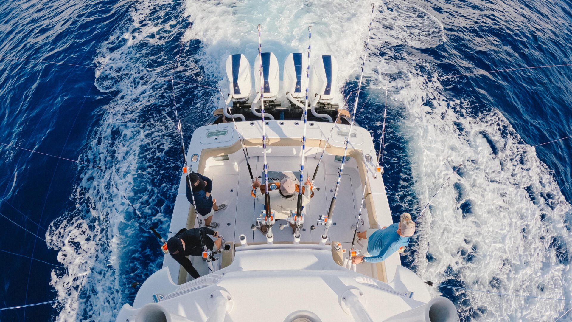 Aerial view of fishing boat running offshore with four anglers and fishing rods at the stern