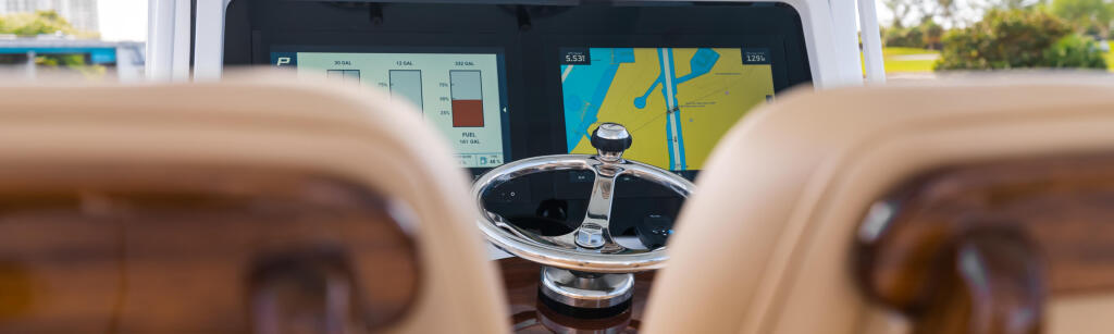 Helm station showing integrated GPS chartplotter and navigation displays with steering wheel in foreground