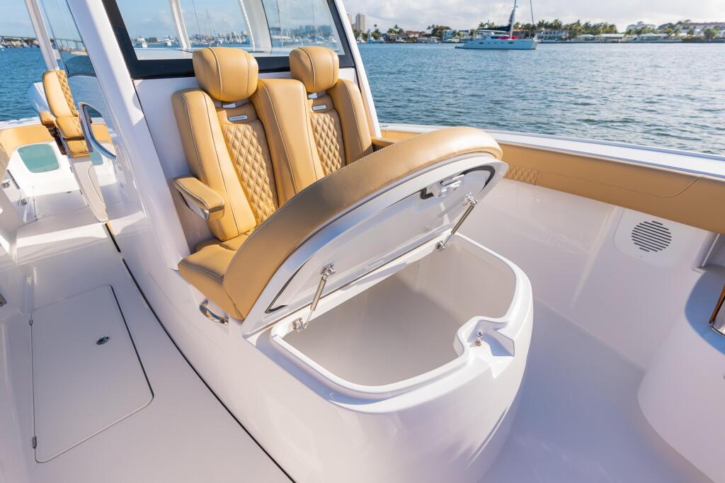 Tan leather helm seats and open cooler storage in the cockpit with waterfront marina view