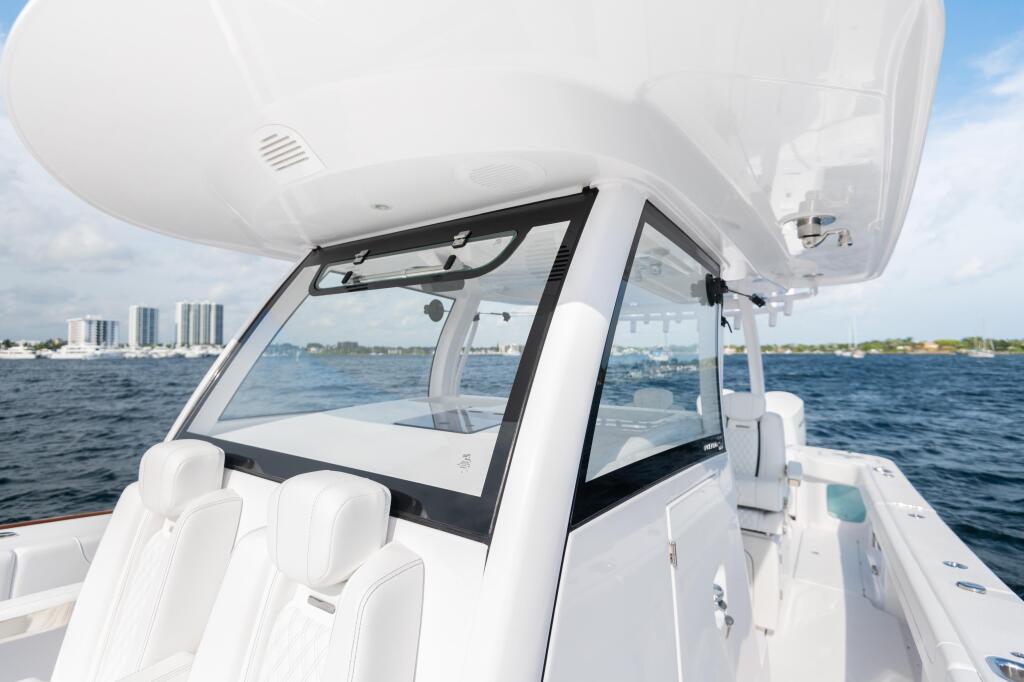 Center console boat with white seating and integrated tempered glass windshield overlooking open water and distant shoreline