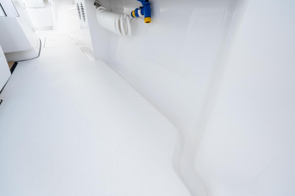 Clean white cabin interior with curved overhead storage and blue-handled freshwater valve system