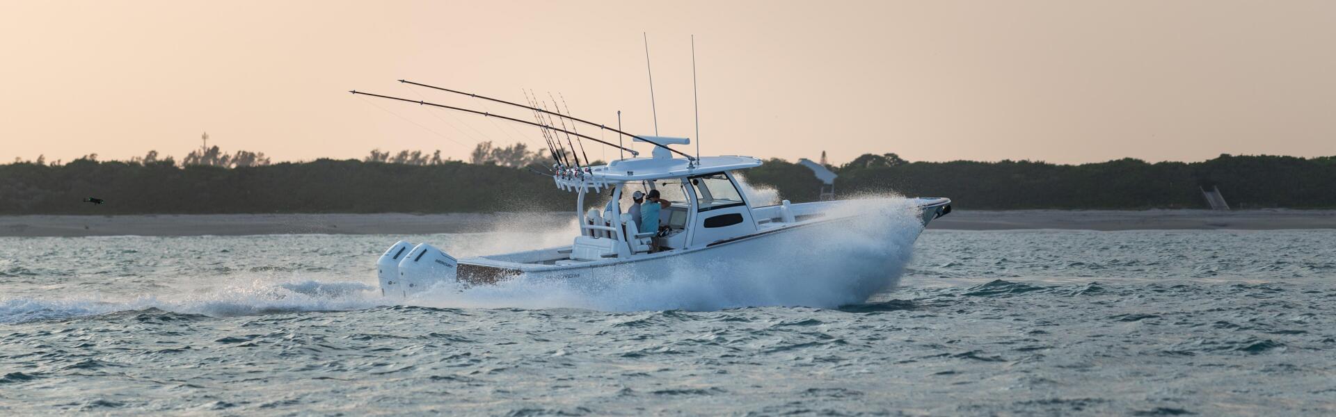 Blue and white fishing boat running at speed through offshore waters with spray kicked up from the hull