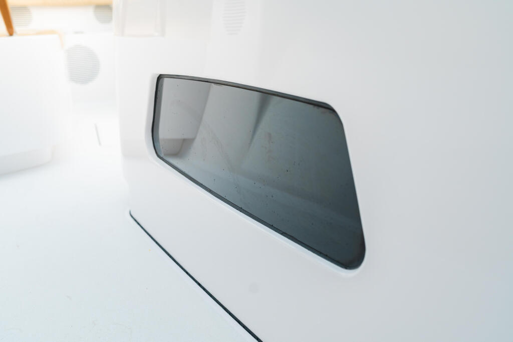 Tinted side window on white boat cabin with dark frame