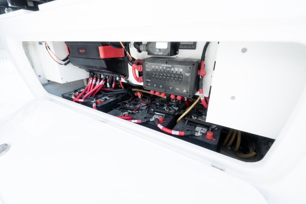 Boat electrical system with red and black cables, battery connections, and control panel mounted in engine compartment