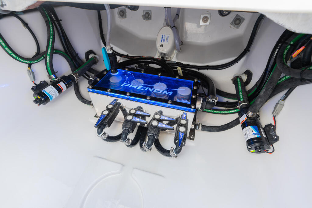 Overhead view of boat's plumbing system with blue Phenom manifold, color-coded hoses, and multiple pumps mounted on headliner