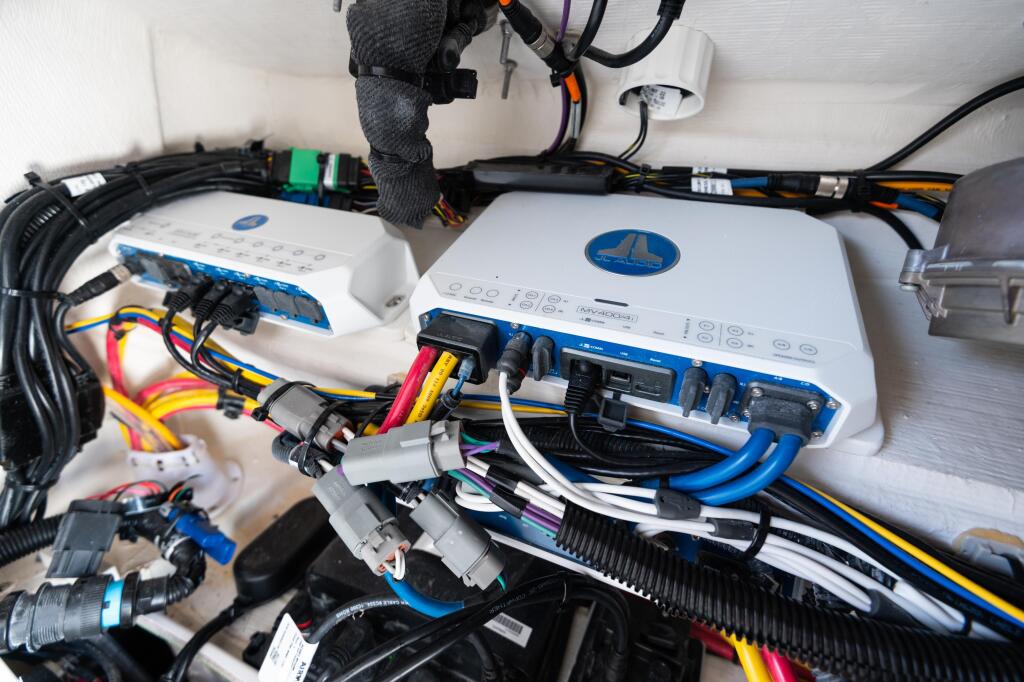 Close-up of marine audio amplifiers and wiring installation with color-coded cables and connectors