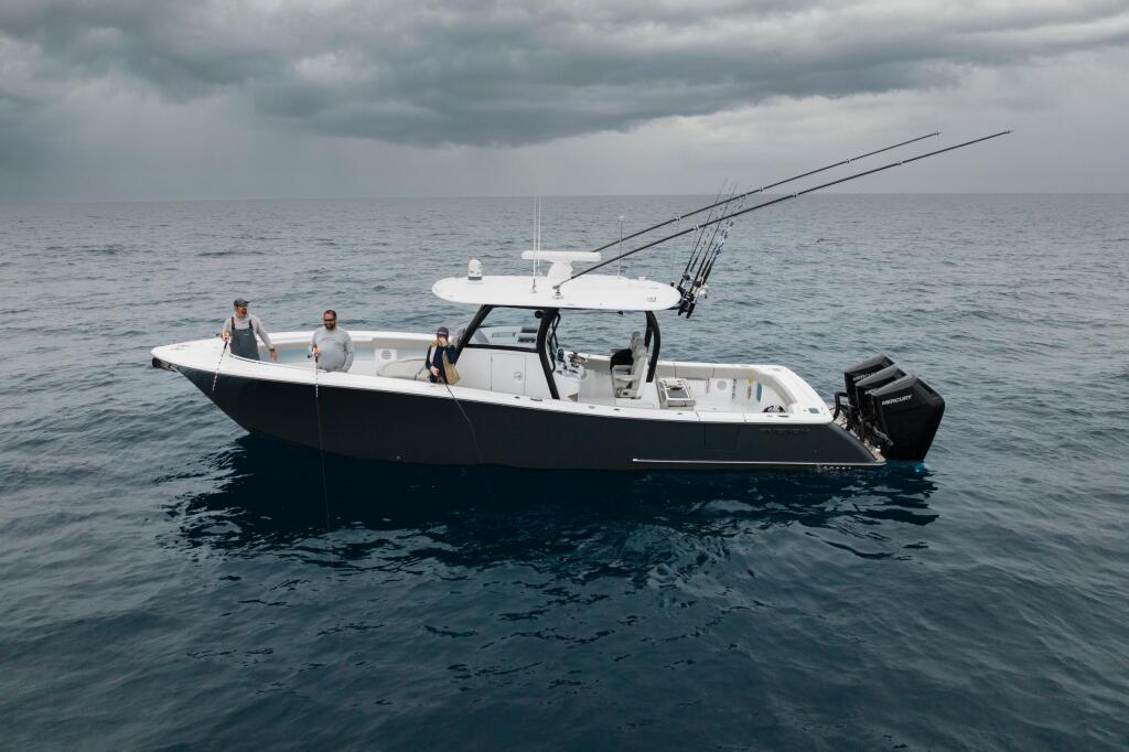 Center console fishing boat with three people aboard in offshore waters under cloudy skies