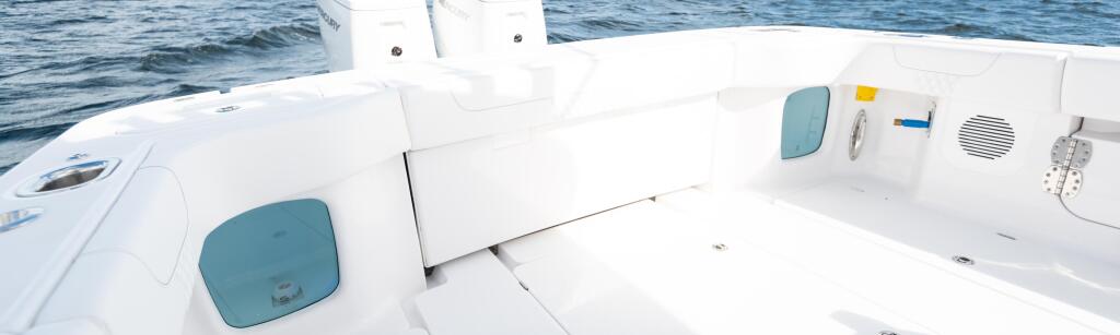 White center console boat with dual outboard engines, tinted windows, and helm controls on calm blue water