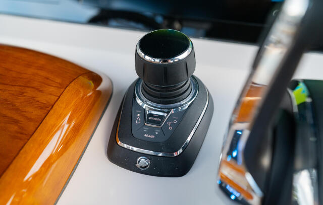 Joystick control at the helm of a boat with varnished wood accents and chrome trim