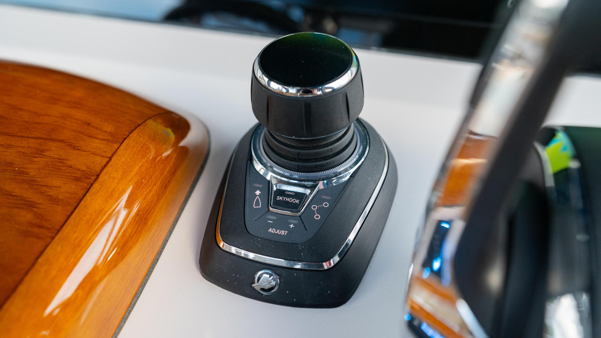 Joystick control at the helm of a boat with varnished wood accents and chrome trim