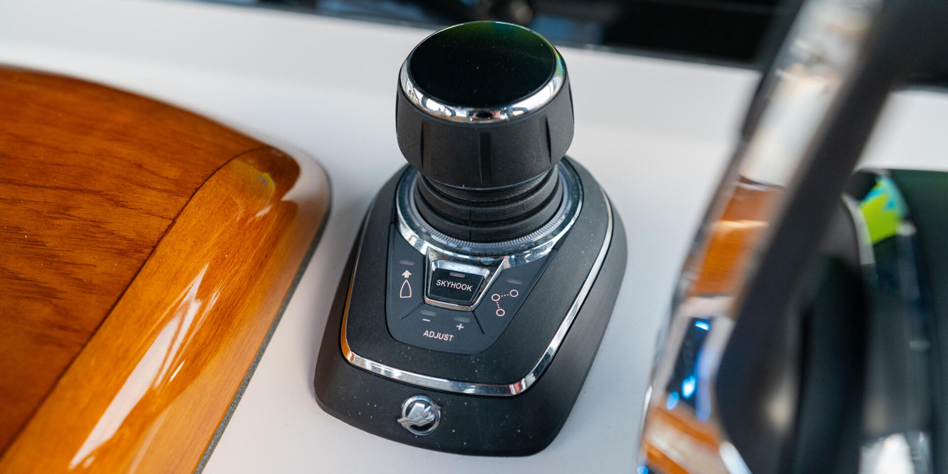 Joystick control at the helm of a boat with varnished wood accents and chrome trim
