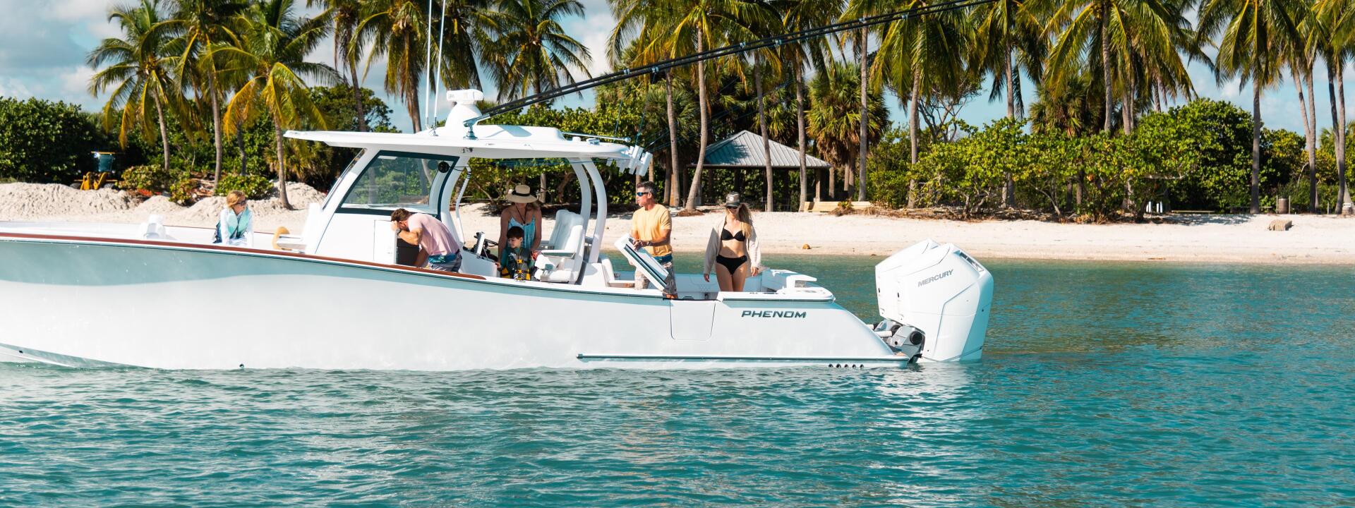Phenom center console boat anchored in turquoise shallow water near a tropical beach with palm trees and sandy shoreline
